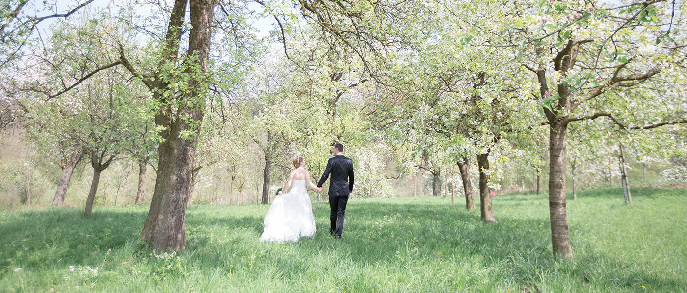 Brautpaar läuft über eine Wiese im Wald