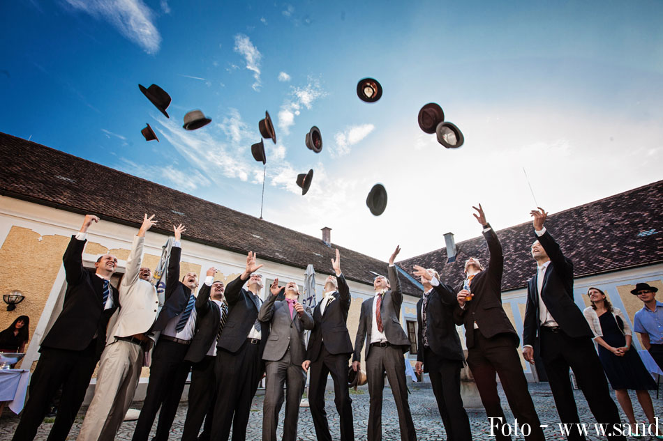 Bräutigam und männliche Hochzeitsgäste werfen ihre Hüte in die Luft